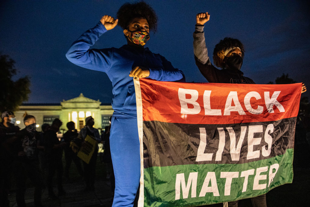 Protesters wearing facemasks stand with a Black Lives Matter...