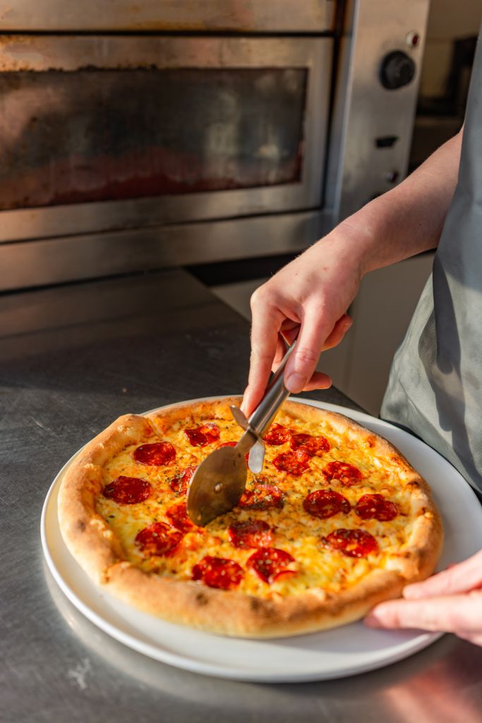 Close-up of chef cutting pizza