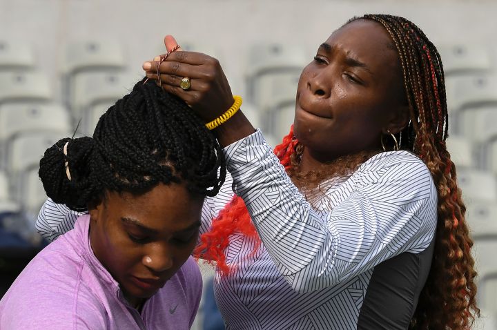 Venus fixes Serena's hair as they prepare for a training session in 2016