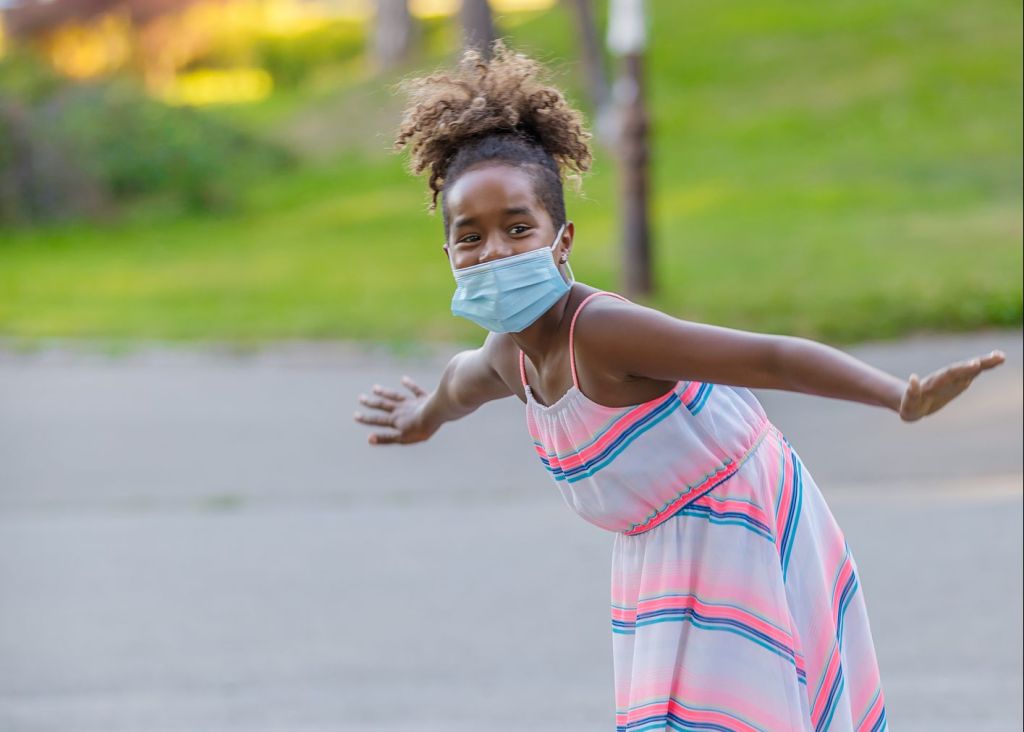 Little African Girl With Protective Mask is Having a Lot of Fun and Riding a Skateboard.