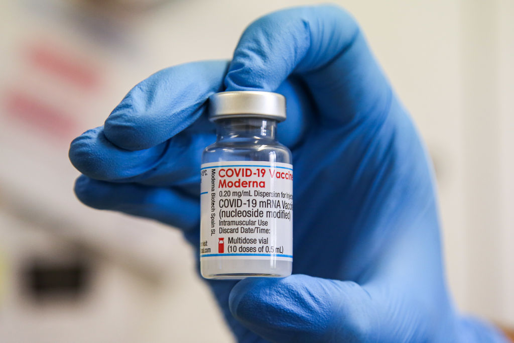 A NHS (National Health Service) health worker holds a vial...