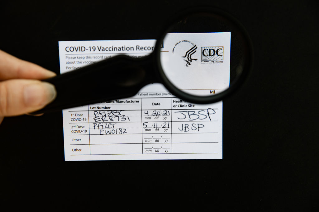 An authentic Covid-19 vaccination card, with CDC logo in magnifying glass