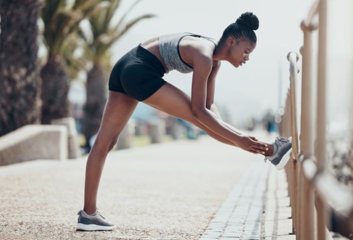Fitness, running and black woman stretching legs outdoors to start marathon training, cardio exercise or urban city sports workout in Brazil. Strong, focus and runner athlete warm up of body wellness