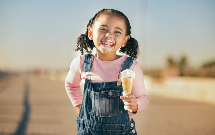 Summer, ice cream and happy portrait of child with smile and dripping face walking on street. Happiness, dessert and small girl laughing with ice cream cone and messy mouth, fun and enjoying holiday.