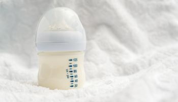 Baby milk formula in small bottle on white fluffy background