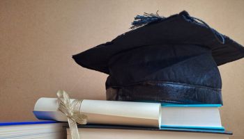 Graduation hat with degree paper on a stack of books