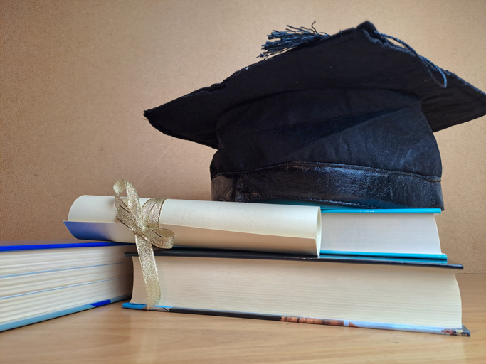 Graduation hat with degree paper on a stack of books