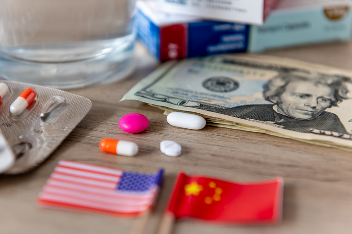 A pharmaceutical, medical competition, conflict, concept with the American and Chinese flags and various medicines on a desk.