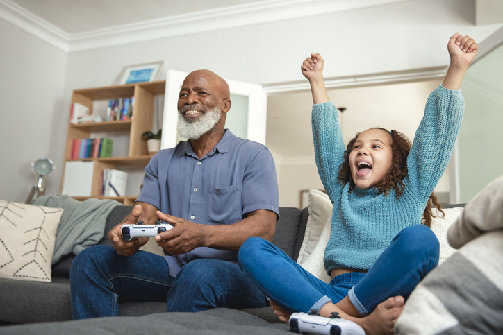 Family Fun: Grandfather and Granddaughter Gaming Together on the Sofa