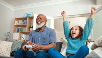 Family Fun: Grandfather and Granddaughter Gaming Together on the Sofa