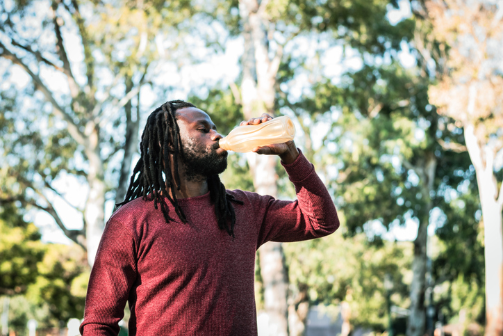 Young man drinking water on a public park