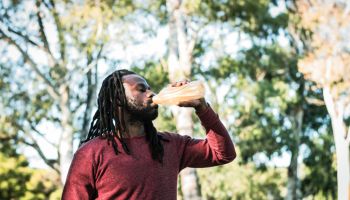 Young man drinking water on a public park