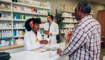 African woman pharmacist selling drugs to a senior customer in a pharmacy