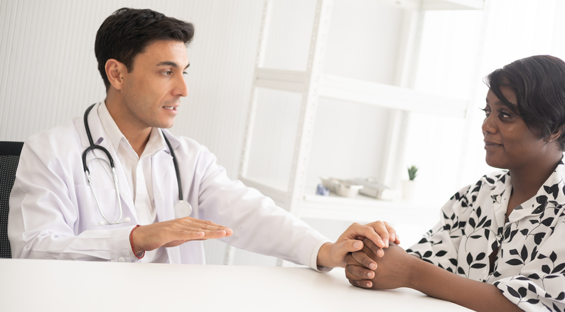 Hispanic physician check-up African American patient with stethoscope at the hospital. Healthcare medical diagnosis and examining on the laptop.