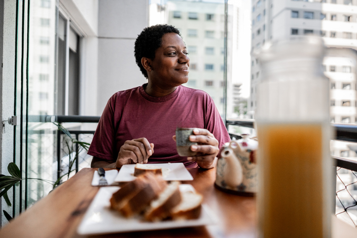 Mature woman having breakfast on the balcony at home