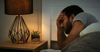 Man, stress and anxiety in bed in the morning with depression, insomnia or mental health in bedroom. Person, sleep apnea or thinking with unhappy, mistake or worried or sleepless in apartment or home