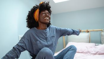 Cheerful African American woman stretching in the bed in the morning