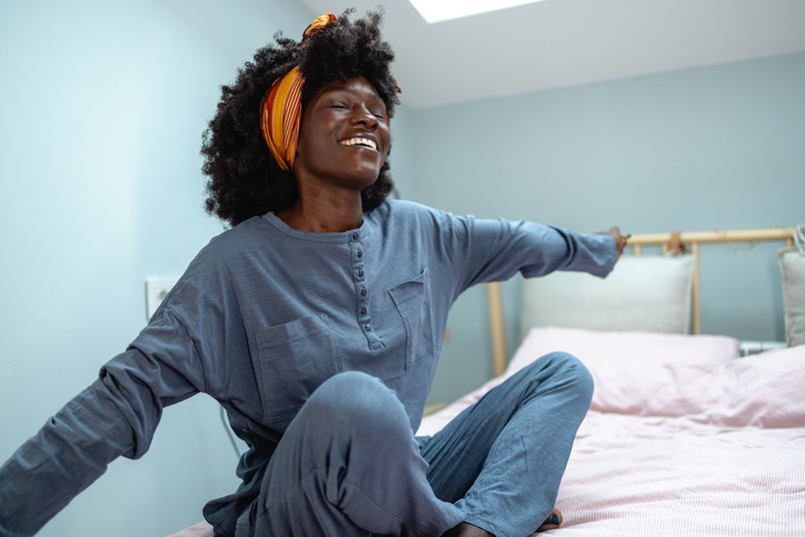 Cheerful African American woman stretching in the bed in the morning