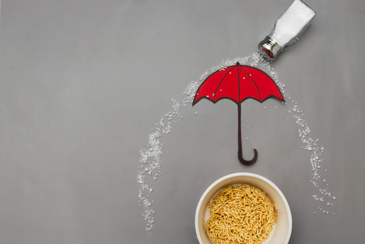 Wok noodles are covered with an umbrella of a lot of salt on a gray background. Please add salt to your food in moderation. Over-salted food is harmful to health. Flat lay