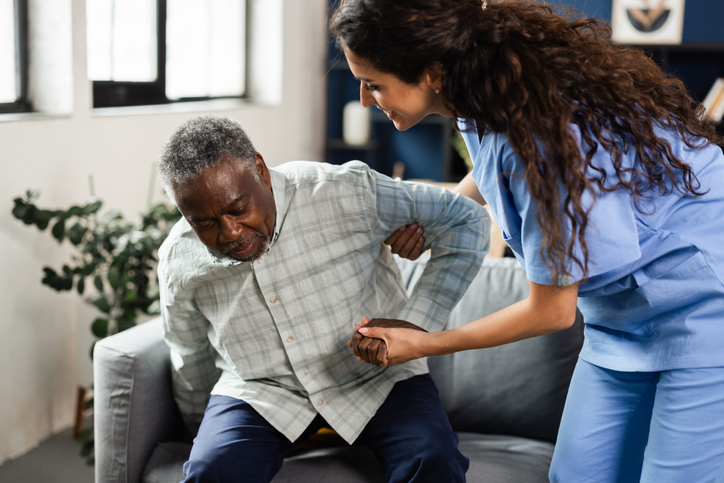 Young doctor helping her senior patient to stand up