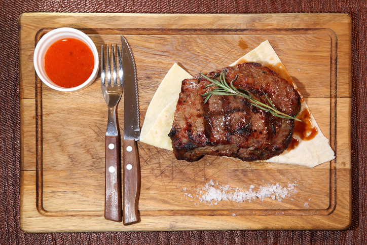 Steak placed on pita bread on a special wooden board. Beef steak on a wooden board.