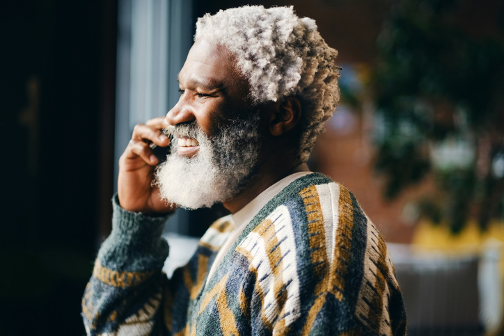 Senior black man, phone call and smile in home for communication, news and listen to contact. Mobile, retirement and happy person in conversation for insurance discussion, pension update or thinking